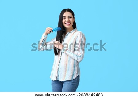 Beautiful young woman with hair comb on color background