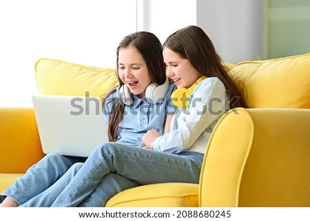 Cute twin girls watching cartoons at home
