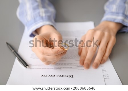 Woman with divorce decree and ring, closeup