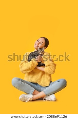 Beautiful young woman with cute cat on color background Royalty-Free Stock Photo #2088691126