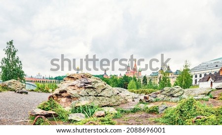 Huge stone, grass and lichen in the center of Moscow in Zaryadye Park against the background of Saint Basil's Cathedral