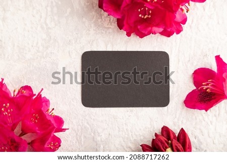 Black business card with purple azalea flowers on gray concrete background. top view, flat lay, copy space, mockup, template, spring, summer minimalism concept.