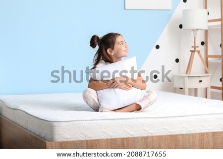 Morning of little girl sitting on bed with comfortable mattress Royalty-Free Stock Photo #2088717655