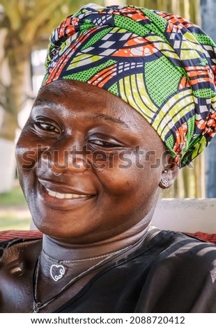 African woman with a hopeful happy smile and traditional headdress sitting in the tropical part of Takoradi Ghana, West Africa