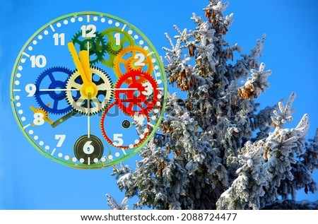 A watch dial with colored gears against a background of blue sky and snow-covered spruce.