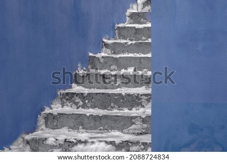 Artistic winter image of street stairs covered with snow and blue walls of building. Trendy color of the 2022 year named very peri