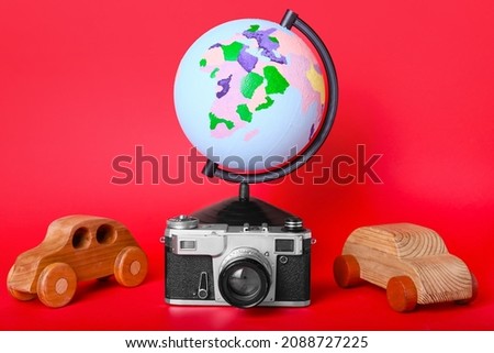 Globe with wooden cars and photo camera on color background