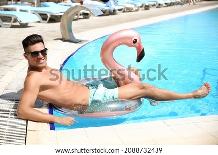 Young man with inflatable ring in swimming pool