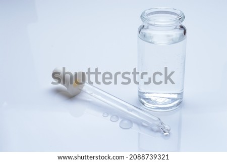 glass transparent jar and a cosmetic pipette with liquid droplets on a white background