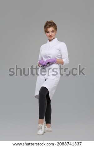 Cute girl honey worker in a white coat thatit isolated on a gray background in full growth.