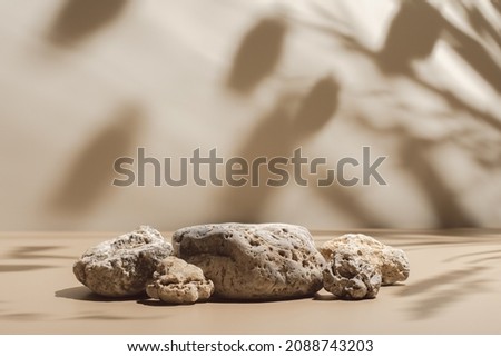 Abstract minimal nature scene - empty stage and composition of stones on beige background and soft shadows of tree leaves. Pedestal for cosmetic product and packaging mockups display presentation Royalty-Free Stock Photo #2088743203