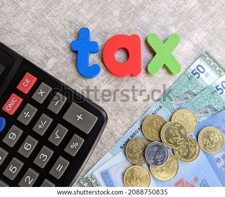 Close -up photos of various Malaysian Ringgit currency values ​​along with a calculator and the word Tax on a wooden background