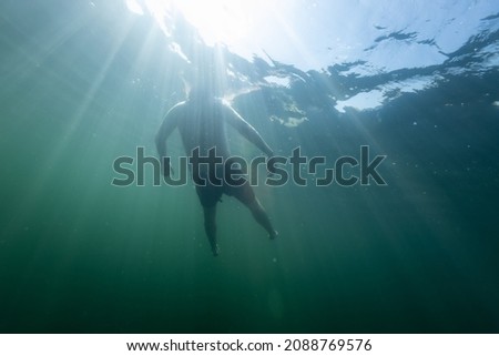 Man falling in a blue sea. Young man bathing and relaxing in the clear and transparent sea water
