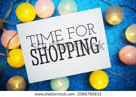 Time for Shopping text on paper card with LED cotton balls decoration on blue background