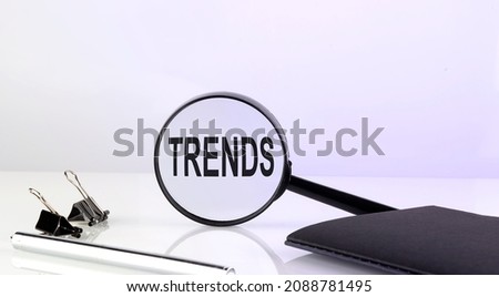 TRENDS concept. Magnifier glass with text with notebook and pen,business