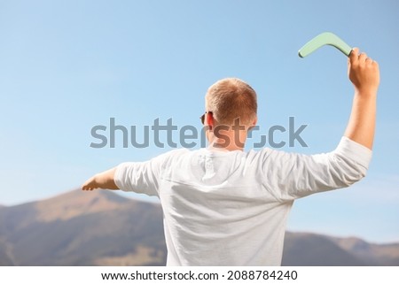 Man throwing boomerang in mountains on sunny day, back view Royalty-Free Stock Photo #2088784240