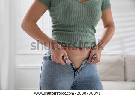 Woman trying to put on tight jeans at home, closeup Royalty-Free Stock Photo #2088790891