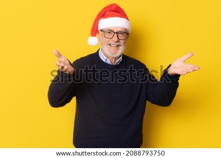 Senior smiling man wearing santa hat standing isolated over yellow background.