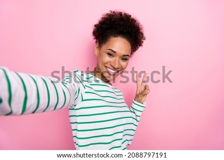 Photo of cool curly young lady do selfie show v-sign wear white shirt isolated on pink color background