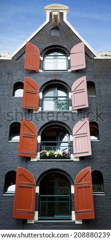 Amsterdam building, front facade of an old converted warehouse with red shutters. 