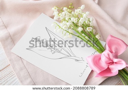 Beautiful lily-of-the-valley flowers, napkin and greeting card on wooden background