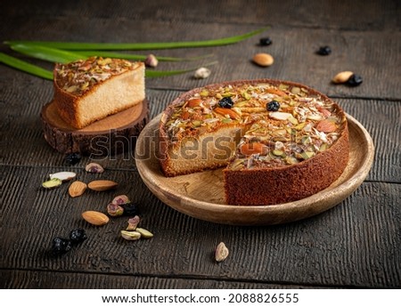 Cake Mawa slice. Mawa cake is a rich, delicious cake made with mawa and atta. serve on wood background with dry fruit nuts. Homemade round half cut sponge cake. Almond, Cashew, Blackberry, Pistachio.  Royalty-Free Stock Photo #2088826555