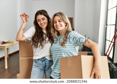 Young beautiful couple smiling happy holding cardboard box and key of new home. Royalty-Free Stock Photo #2088831346