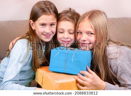 Sisters congratulate their brother Two girls congratulate the boy on his birthday. They give him gifts and hugs