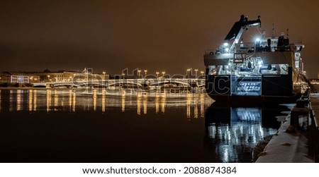 The panoramic footage of the winter night city Saint-Petersburg with picturesque reflection on water, big ship moored near Blagoveshchensky bridge or lieutenant Schmidt, Isaac cathedral on background