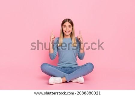 Full size photo of young girl sit floor indicate fingers empty space ads recommend suggest isolated over pink color background