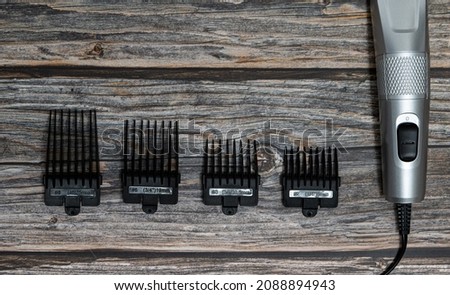 New metal wireless hair clipper, with set of attachments for different lengths, brush for cleaning. Trimmer battery for cutting and removing excess hair on gray background. Styling beard, temples. Royalty-Free Stock Photo #2088894943