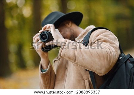 Black man standing on a road and take a photo on a professional camera