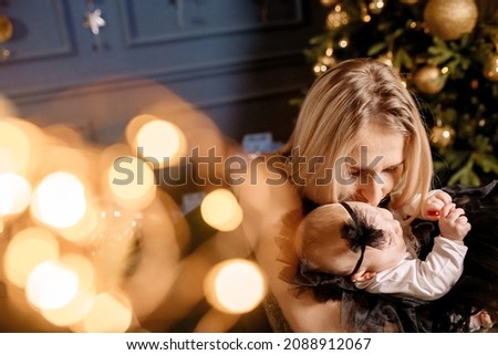 Young beautiful family with two daughters in smart clothes are hugging in the living room, celebrating the christmas holiday