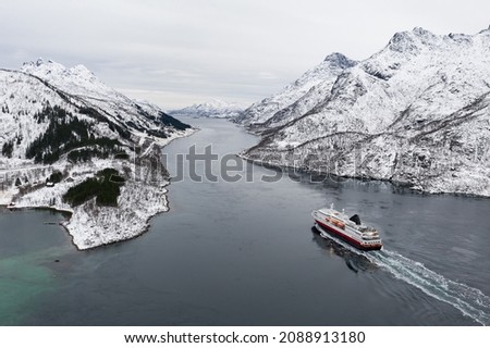Aerial view of fjord in cold winter weather with Hurtigruten ferry turist boat on the sea. Lofoten near Trollfjorden. Panoramatic photography in foggy weather.
