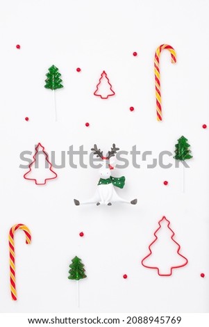 Minimal New Year composition of Christmas reindeer among Christmas trees and red winter berries. New year concept. Gift wrapping pattern 