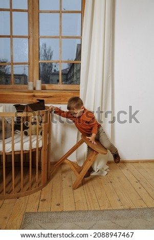 little boy playing in the room in a brown sweater