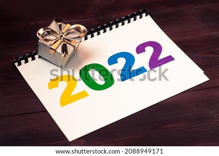 2022 multicolored numbers on a piece of paper and a gift lying.