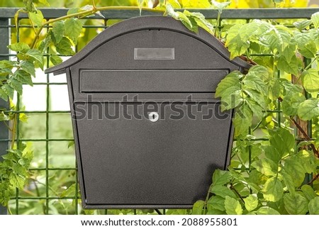 one gray metal mailbox on a wire fence and green leaves  Royalty-Free Stock Photo #2088955801
