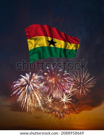 Holiday fireworks in evening sky and flag of Ghana for National Independence day