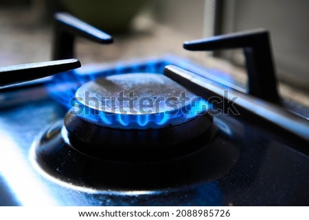 Cooker as heater. Blue flame from gas hob produce greenhouse gas emissions. Wastage of natural resources. Kitchen stove grate on a burner fuelled by combustible natural gas or syngas, propane, butane. Royalty-Free Stock Photo #2088985726