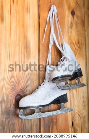 Pair of vintage skates hanging on a wooden background.