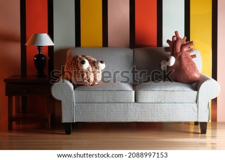Anthropomorphic heart versus brain sitting together on a sofa as concept for emotions versus logic Royalty-Free Stock Photo #2088997153