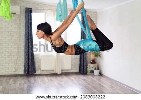 Full length of fit young woman doing antigravity yoga exercises in studio