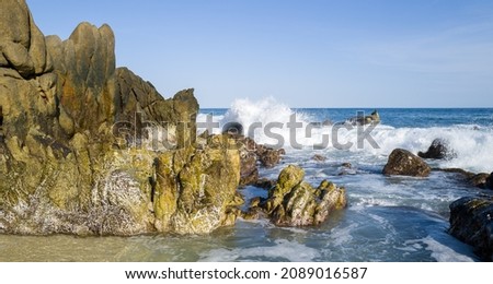 ocean waves splashing against the rocks on the beach