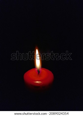 Red candle with flames in black background
