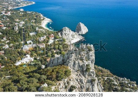 Aerial view of man tourist in red jacket standing on the rock top of cat mountain enjoying landscape of Simeiz village with Diva and Penea rocks in background. Crimea