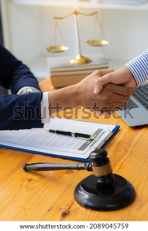 Picture of a businessman lawyer shaking hands with documents, contracts, client cooperation agreements, and hammers at the tables of a tax advisory and real estate concept company.