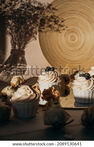 Delicate blueberry cupcakes stand on a round mirror as a composition, photo for content