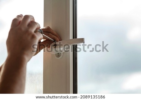 Window handle Installing by screwdriver. Making a house cozy and warm. Security  window handle Lockable Protection Safety Royalty-Free Stock Photo #2089135186