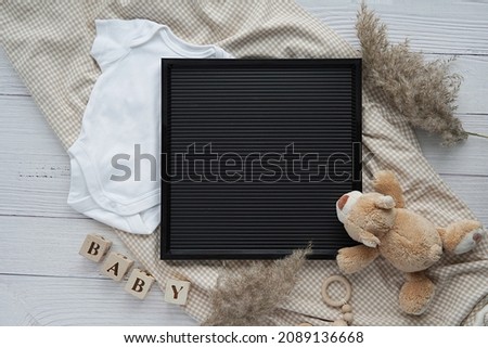 Black letterboard mockup, baby bodysuit, toys, pampas grass, blanket, pregnancy announcement, baby waiting. Royalty-Free Stock Photo #2089136668